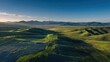© juwairiya_nameera - Solar farm on green hills with mountain range at sunset