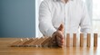 © Olivia - Businessman hand stopping falling wooden domino blocks to prevent chain reaction representing risk management, crisis prevention, insurance protection and strategic intervention