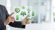 © NurFatimah - Businessman interacting with holographic green energy icons, renewable power concept, sustainable technology and eco-friendly innovation for a cleaner future.