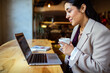 © Marko Geber - Businesswoman using laptop and drinking coffee in cafe
