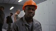 © Framestock - Portrait of Dedicated African American Male Worker in Orange Hard Hat, Looking Confidently Into Camera With Serious and Responsible Expression in Dressing Area. Professionalism in Heavy Industry.