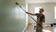 © antuanetto - Professional man painting interior wall with roller extension pole in modern apartment for home improvement and renovation concept, remodeling workspace background