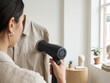 © Achmad - Woman Steaming a Linen Shirt with a Handheld Garment Steamer for a Wrinkle-Free Finish