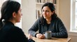 © ryker - Middle eastern woman listening attentively at wooden table with mug, cozy cardigan and soft natural light conveying warmth and calm conversation
