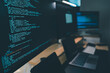 © onephoto - Close up of computer monitors displaying source code in a modern workstation with laptop and digital devices, showing software development workflow, programming process, and technical productivity in