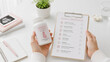 © Dian - Close-up of hands holding prenatal vitamins alongside a prenatal care checklist in a clean, minimal healthcare setting. Concept of pregnancy care, maternal health, and healthy lifestyle