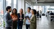 © Zero One Studio - Modern Office Setting Features Diverse Team discussing project in hallway. People standing with documents in bright open office with copy space and natural light.