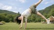 © AiPhoto - キャンプ場の芝生で元気に側転をして遊ぶ女性