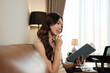 © Parichat - Young woman reading notebook holding pen on sofa