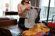 © Parichat - Woman organizing clothes on a sofa at home