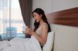 © Parichat - Young woman enjoying morning coffee in comfortable bed