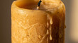 © Dani - Close-up of a textured, amber-colored pillar candle with melted wax dripping down its side, showcasing the warm, cozy ambiance and the effects of burning