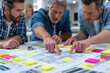 © Juan - engineers reviewing blueprint with sticky notes during project planning session