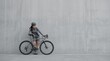 © Saif Ali - Stylish female cyclist in modern athletic gear, leaning on a sleek road bicycle against a minimalist concrete wall, embodying urban active lifestyle and fitness.