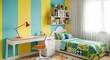 © Waqf - A vibrant and modern kids bedroom with yellow and turquoise striped walls, a white desk and chair, and a colorful patchwork quilt on the bed