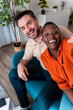 © Marko - Smiling friends sitting together in a cozy living room during the daytime