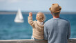 © Ruzana - Elderly caucasian male with child enjoying ocean view and sailing boat