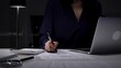 © volha_r - Businesswoman working late night typing on laptop at home office desk with documents and calculator. Audit and taxes in business