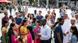 © Lucas - Diverse group of people gathered in a sunny city square, engaging in conversation and social interaction, representing multiculturalism and community