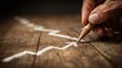 © Delima - Mature hand draws an upward trending line with a sharpened drawing instrument on textured wooden surface
