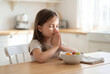 © Meow Creations - Young girl praying with hands together before eating a healthy meal. concept of faith and gratitude