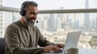 © Fridocha - Happy Middle Eastern Man Working Remotely on Balcony.