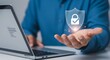 © Tim - Hand presenting digital shield with lock icon, laptop in background, cybersecurity concept