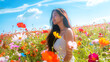 © Chayanan - A young woman enjoying a beautiful day in a field of colorful wildflowers under a clear blue sky.