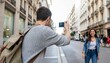 © GreenLand - Man takes photo of woman on city street with buildings