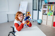 © Halfpoint - Female student in wheelchair presenting robotic project in front of classroom.