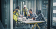 © Gorodenkoff - Executives and Construction Consultants Meet in a Glass Office to Review Blueprints, Align Budgets, Set Milestones, and Plan Risk, Compliance, and Stakeholder Communication Strategies for Business