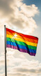 © PhotoArtHub - Rainbow flag waving against a cloudy sky with sunlight breaking through, symbolizing pride, diversity, and LGBTQ+ rights.