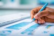 © Generative AI - Close-up of hand holding pen analyzing financial data charts and graphs on desk with keyboard