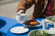 © RooM The Agency - Close-up of a man sitting at a table drinking a cup of coffee and eating a roast beef salad and cherry brioche bun