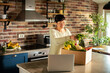 © Davor - Smiling woman unpacking fresh produce delivery in home kitchen