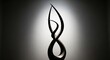 © Hungarian - Abstract sculpture with flowing curves stands against a softly lit background.