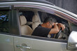 © Daniel Pawer - Asian male driver asleep at the wheel. Young man sitting in his car, his hands and head on the wheel. Campaign for safe driving. Working overtime