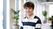 © Vasiliy - Portrait of a smiling young man in a modern office. Happy male employee wearing a striped shirt looking at camera. Confident corporate intern
