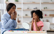 © Prostock-studio - Young black woman speech-language pathologist exercising with adorable little girl with bushy hair, working on word sounds, kid looking at mirror and touching her mouth, clinic interior