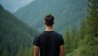 © Vadym - Man in black t-shirt looks at green mountain forest. Back view of guy wearing casual clothes on nature path. Young person enjoys scenic mountain landscape view.