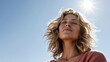 © Newleks - Woman enjoying warm sun and fresh air outdoors, eyes closed in peaceful contentment, feeling carefree and healthy against a clear blue sky, experiencing well being, freedom, and vitality
