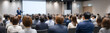 © pattozher - Engaging Presentation: A captivating presentation unfolds as a speaker commands attention on stage, addressing a rapt audience in a modern conference room setting.