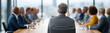© pattozher - Leading the Vision: A corporate leader, viewed from behind, stands before a boardroom table, commanding attention and direction among a team.