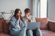 © Daniel - Young couple sits on a sofa looking shocked and worried while viewing something upsetting on a laptop, conveying stress, anxiety, relationship tension and financial or personal bad news at home.