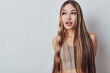 © SHOTPRIME STUDIO - Young woman with long braided hair wearing a sleeveless top standing against a light background looking sideways with a thoughtful expression. Beauty and fashion concept.