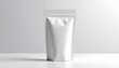 © andre - A mockup of a shiny silver foil stand-up pouch packaging on a white table against a plain background for product display purposes