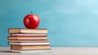 © Nasreen - Colorful stack of educational books with fresh red apple on top against blue background, academic learning and back to school concept featuring classroom study materials, knowledge resources and stude