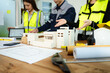 © Nuttapong punna - Creative architect projecting on the big drawings with architectural project at construction site at desk