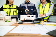 © Nuttapong punna - Engineer team in safety helmets discussing house model and blueprint. Construction planning, architecture design, project management