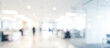 © birulaut - Blurred image of a modern office space with people working. The background features white walls, desks, and soft lighting, creating a professional atmosphere.